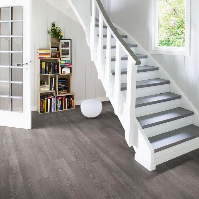 Dark oak wood effect flooring in a hallway with a bookshelf and quirky staircase