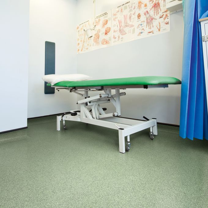 Hospital room with a bed and green coloured flooring