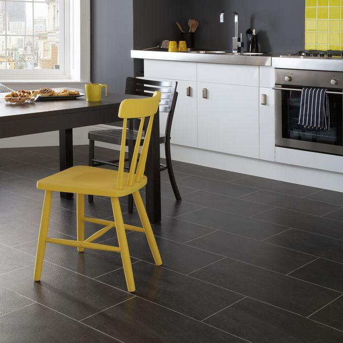 Modern kitchen area with dining table and chairs featuring dark slate effect flooring