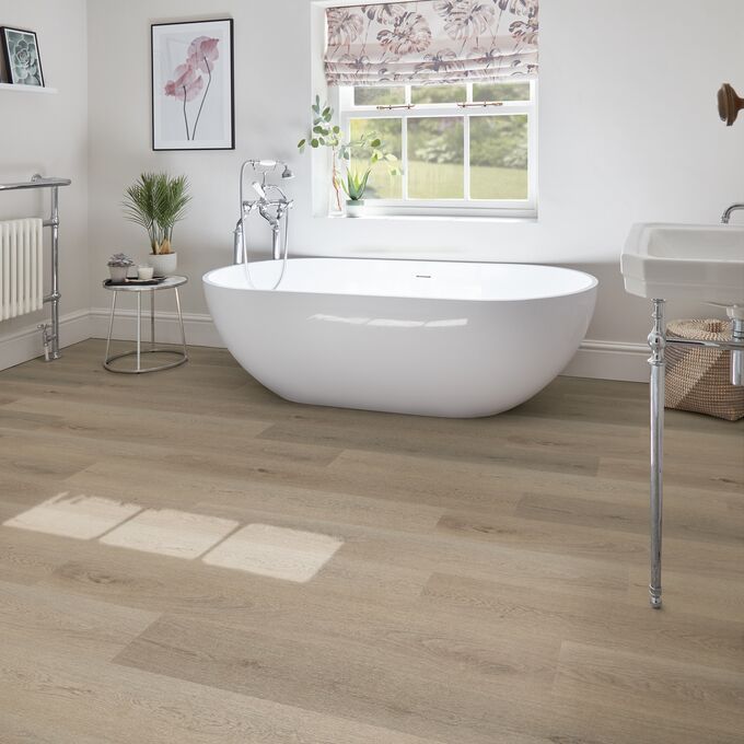 Light oak effect flooring laid within a large family bathroom